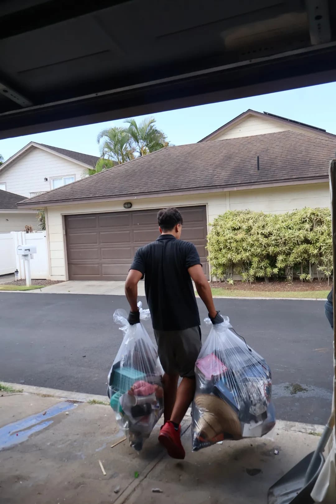 A HI End Services team member carrying bags out of a garage cleanout